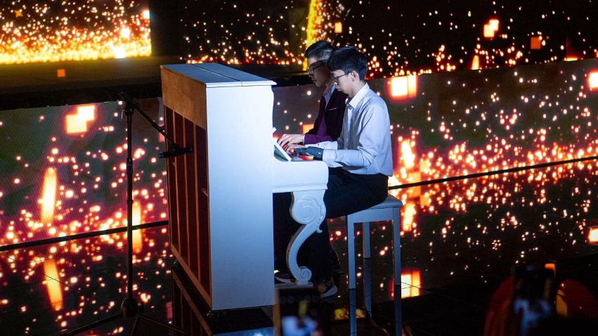 智能仿生手使用者古月與少年鋼琴家舒海峰合奏。主辦方供圖